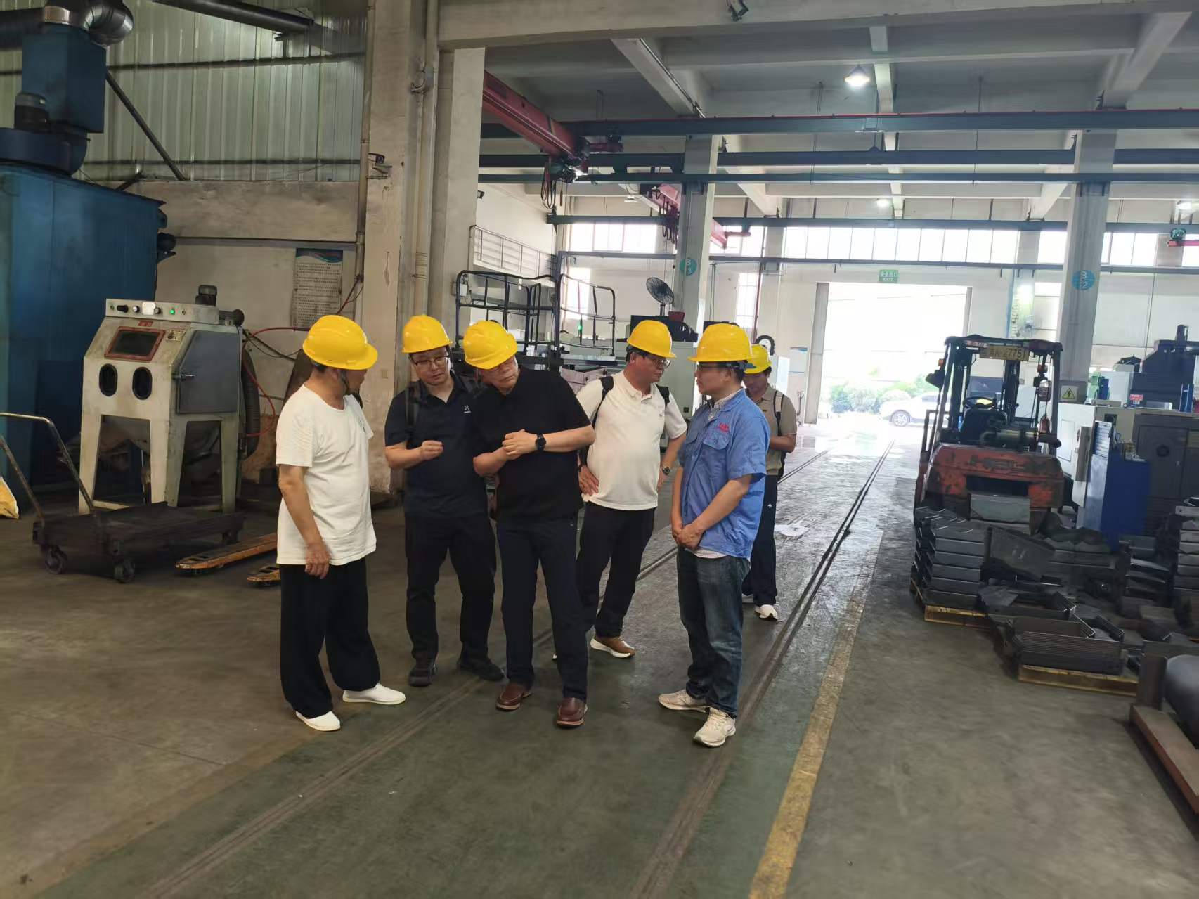 Visitors reviewing sandblasting equipment in the machining workshop